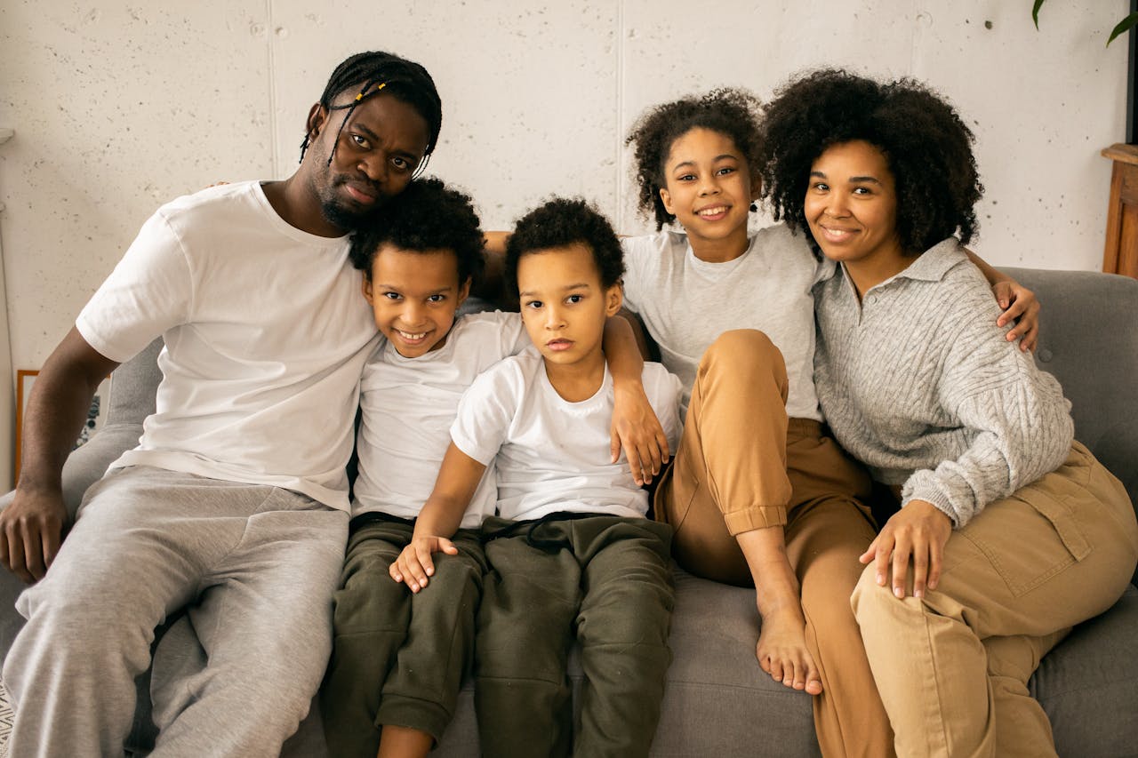 A joyful family of five sitting together on a couch, smiling and bonding