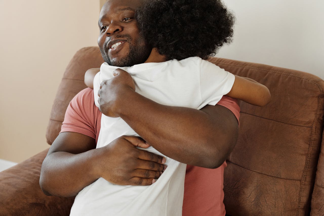 Father embracing his young son in a warm hug on the couch