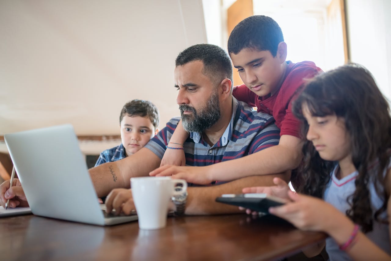 Father working at laptop surrounded by his children